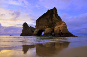 Zonsondergang op Wharariki Beach met zicht op twee van de Archway Islands. 